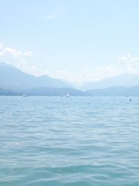 Scenic view of sea by mountains against sky