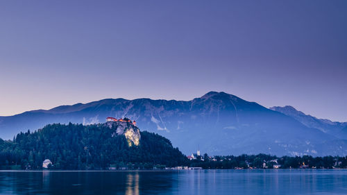 Scenic view of lake and mountains against clear blue sky