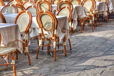 Empty chairs on sidewalk in city