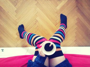 Low section of person wearing canvas shoes on hardwood floor