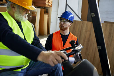 Man talking to worker on forklift in factory