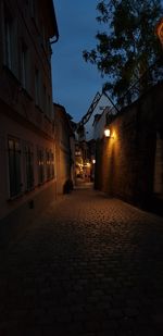 Empty alley amidst buildings at night