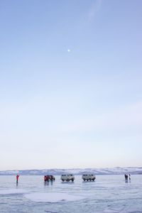 Off-road vehicles and people at frozen lake baikal against sky at dusk