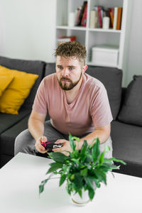 Portrait of young man using mobile phone while sitting on sofa at home