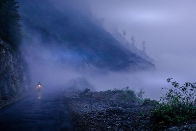 Person riding motorcycle on road against mountains