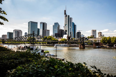 Modern buildings by river against sky in city