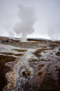 Smoke emitting from mud on landscape against sky