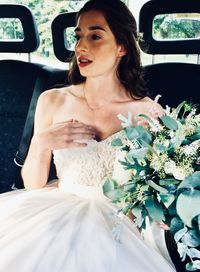 Bride with bouquet looking away while sitting in car