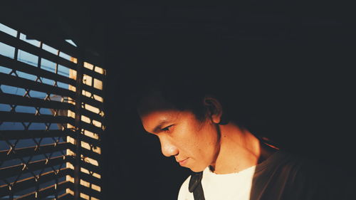 Sunlight falling on young man standing by window in darkroom