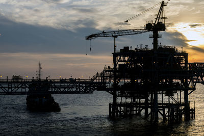 Silhouette of pier in sea against sunset sky