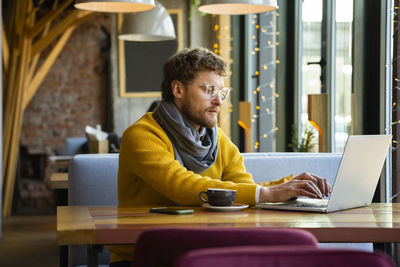 Man using mobile phone while sitting on table