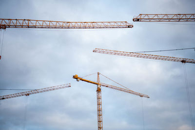 Low angle view of cranes against sky