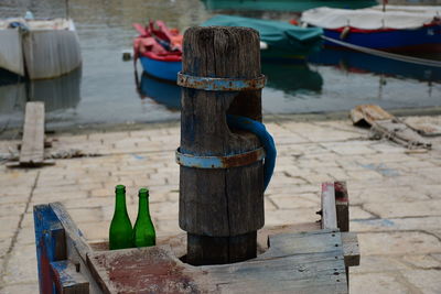 Close-up of wooden post with beer bottle on pier by sea