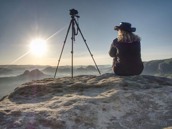 Rear view of person photographing on rock