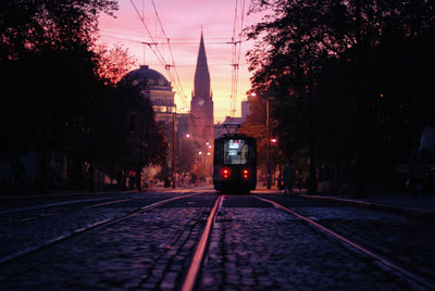 Railroad tracks by road in city against sky