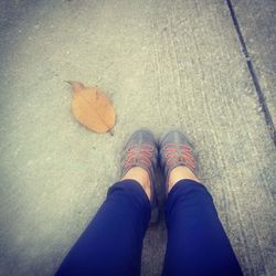 Low section of woman standing on autumn leaves