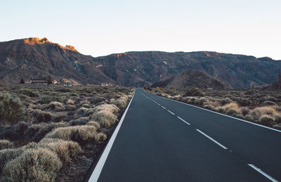 Road leading towards mountains against sky