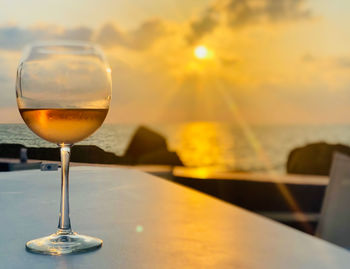 Close-up of wineglass on table against sky during sunset