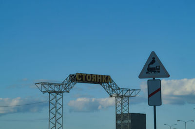 Low angle view of road sign against blue sky