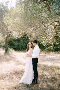 Couple standing on field against trees