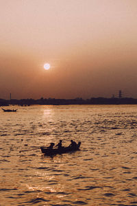 Silhouette ducks swimming in sea during sunset