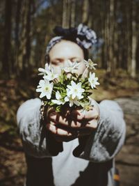 Woman holding flowers in forest