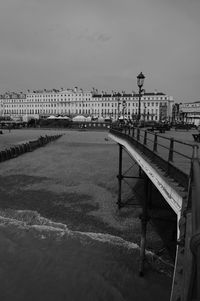 Bridge over river by city buildings against sky