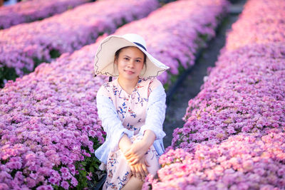 Portrait of woman standing amidst flower plants on field