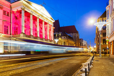 Tram in a motion blur at night city center and view on theater, wroclaw, poland