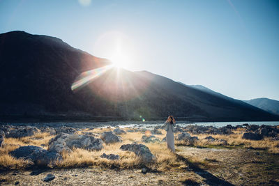 Woman standing on field against mountains