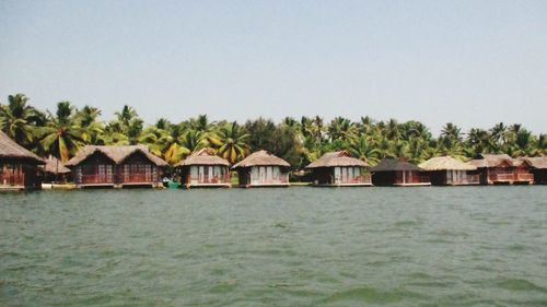 Stilt houses in sea against clear sky