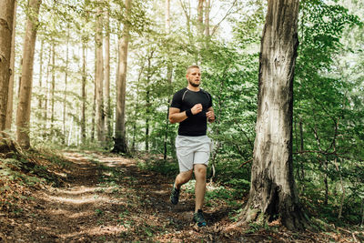 Full length of young man running in forest