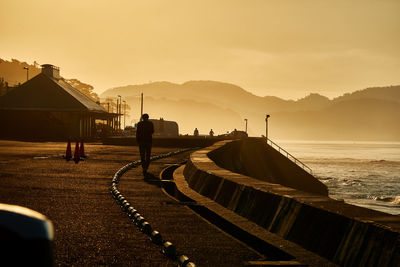 Scenic view of sea against sky during sunrise with silhouette people