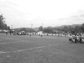 People playing soccer on field against sky