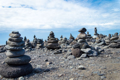 Stack of pebbles on beach against cloudy sky