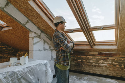 Architect with arms crossed standing near window