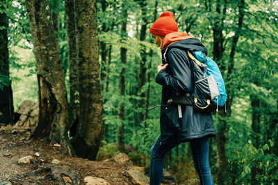 A young female tourist with a backpack walks along a forest mountain path