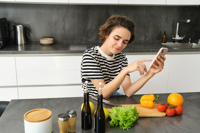 Young woman using mobile phone in kitchen