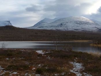 Scenic view of lake by snowcapped mountains against sky