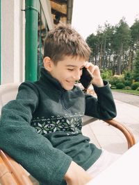 Full length of boy sitting on mobile phone