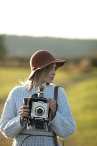 Young woman with camera standing on field