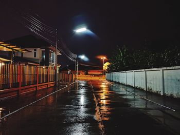 Illuminated street lights on road during rainy season at night