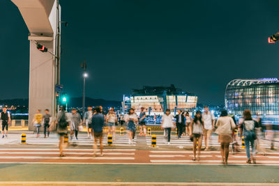 People crossing street in city at night