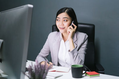 Young woman using mobile phone while sitting on table