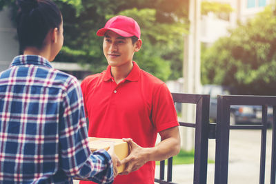 Man delivering package to female customer at gate