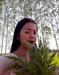 Portrait of smiling young woman against trees