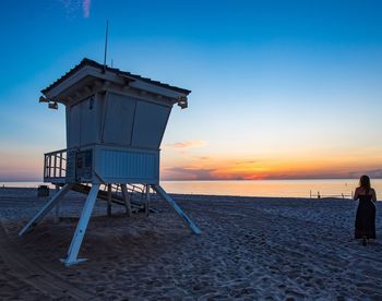 Lifeguard hut on beach against sky during sunset