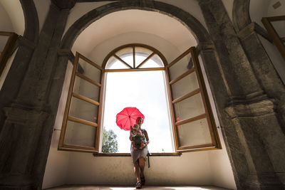 Woman standing by window of building