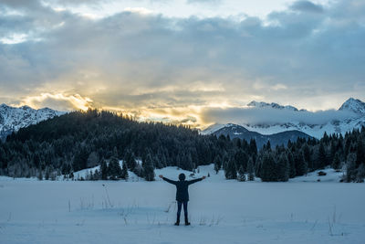 Woman standing on snow field against sky during winter