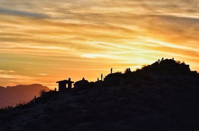 Silhouette people on mountain against sky during sunset
